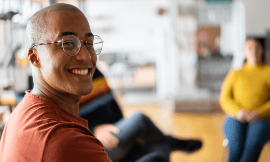 Man smiling in a room with other professionals